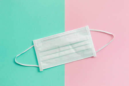 Top view new protective face mask on pink and bright green backgroundの写真素材