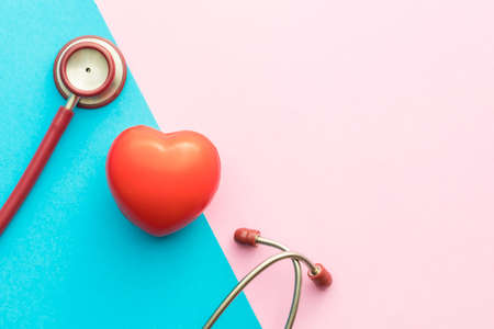 Top view red stethoscope and red heart shape on pink and blue background