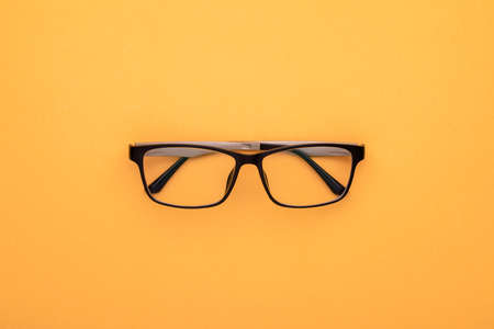 Top view new eyeglasses on yellow background. Copy space for text or design