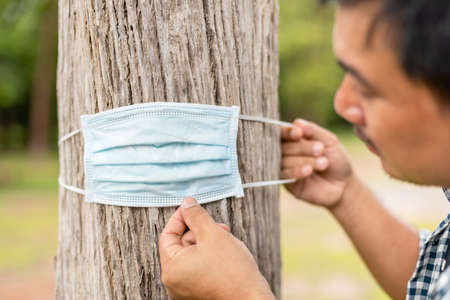 Asian man wearing protective mask for the tree. Take care the earth, Love tree and nature or environment conceptの写真素材