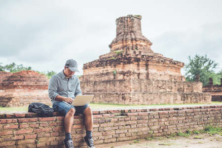 Asian tourist working and using laptop at Sukhothai historical park, Thailand. Vacation and holiday conceptの写真素材