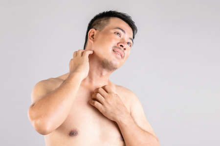 Health care or Itchy or Tinea Cruris concept : Portrait of people using hands to Scratching on his body. Studio shot on grey backgroundの写真素材