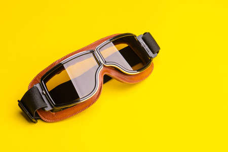 Close up new brown vintage wind goggle. Studio shot isolated on yellow backgroundの写真素材