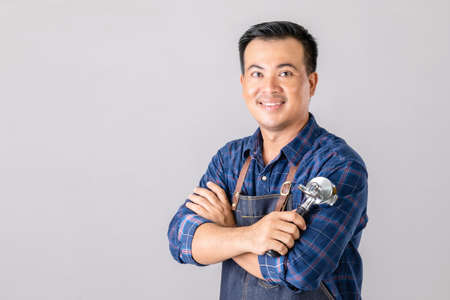 Portrait Asian man in barista uniform holding Coffee Bottomless Portafilter in studio isolated on grey backgroundの写真素材