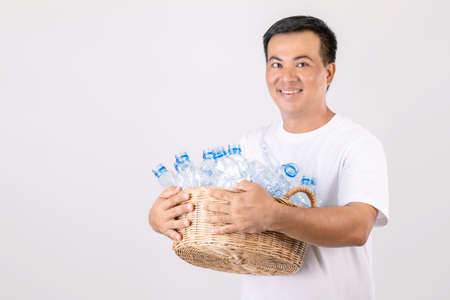 Recycle plastic concept : Portrait Asian man holding basket of empty clear old water bottle. Studio...
