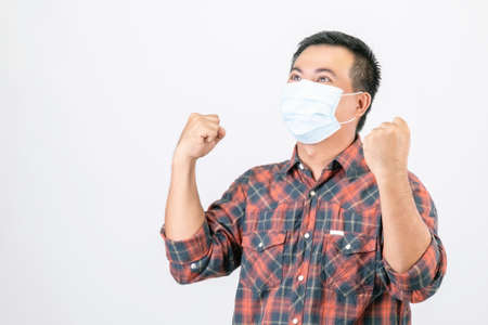 Passed bad situation concept : Asian man wearing protective face mask in action of glad, victory or...