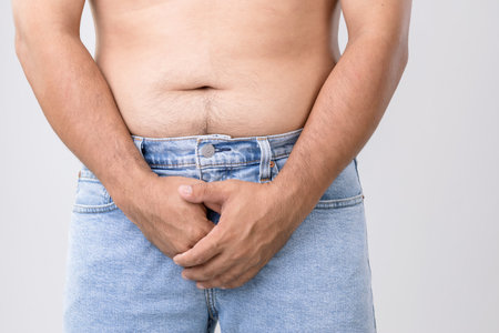 Pain on penis concept : Man use his hands to press on his penis on grey background. Used for Prostate cancerの写真素材