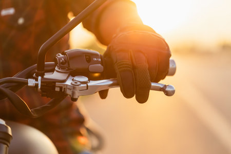 Safe ride concept. Macro left hand of motorcyclist wearing riding glove on the clutch. Outdoor shooting on the road with copy spaceの写真素材