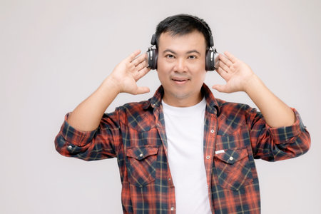 Portrait Asian man listening song or music from black headphone. Studio shot isolated on grey...