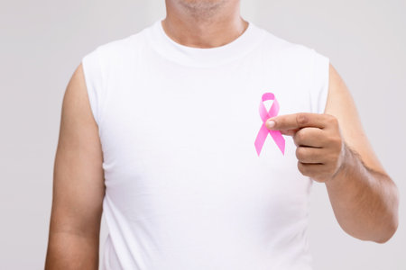 Breast cancer in men concept : Portrait Asian man and pink ribbon the symbol of breast cancer campaign. Studio shot isolated on grey backgroundの写真素材