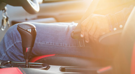 Car driving concept : Close up driver hand fastening on seat belt inside the modern car. Car...