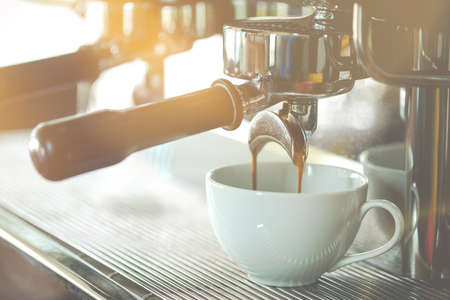 Close up coffee extraction from coffee machine to white cup in coffee shop. Food and beverage...