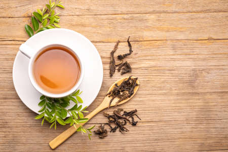White cup of hot tea and dry tea leaf on wooden table backgroundの写真素材