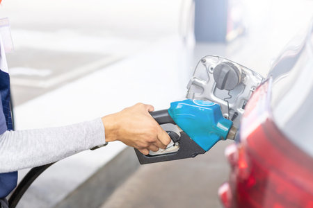 Close up hand of refueling worker are filling fuel to car in Petrol station. Focus on fuel nozzle...