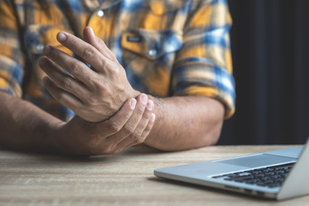 Injuries or Illnesses that can happen to office worker. Man is using his hand to cover over wrist because of numbness, hurt,  pain or feeling ill. Healthy concept.の写真素材