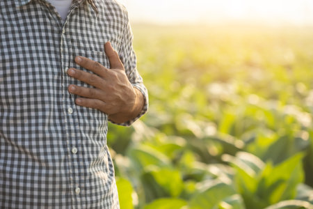 injuries or Illnesses, that can happen to farmers while working. Man is using his hand to cover over left chest because of hurt,  pain or feeling ill. Health of agriculturist concept.の写真素材