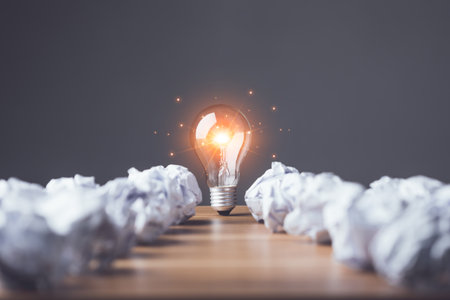 Finding the new inspiration concept, Light bulb with white used and crumpled paper on wooden table. Use for the idea of future creative innovation, Learning, Education or working, Studio shot.の写真素材