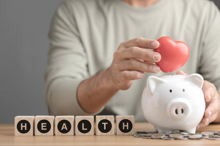 Financial for health concept, The idea of saving money for health and life, Man keeping a red heart in white piggy bank on desk. Health, health check up or saving money concept. Studio shot.の写真素材