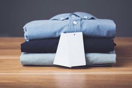 Close up stack of new color men shirt on wooden desk with dark space grey background. Mens fashion...