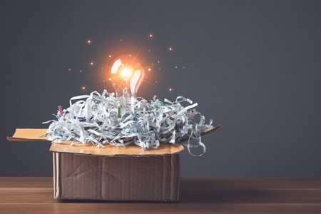 Find the new idea from past failures, Creative new design thinking for work, Light bulb and pile scrap paper from shredder on wooden office desk, Can use for reuse and recycle concept. Studio shot.の写真素材