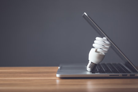 Clear light bulb with modern laptop on the office desk with grey space wall background. Use for the idea of future creative innovation, Learning, Education or working, Studio shot.の写真素材
