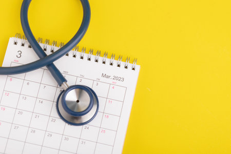 Health check up schedule concept, The idea of time for healthcare, Close up stethoscope and 2023 desk calendar on yellow background. Yearly planning for health check up concept.の写真素材