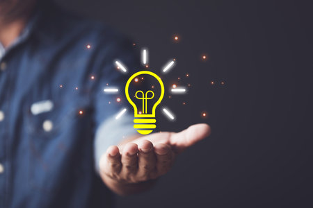 Ideas for designing new things, Using new technologies to innovate in the future, hand holding a blue illuminated light bulb. Brigh and creativity concept.の写真素材