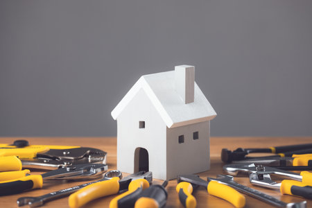 Home repair, Renovation or Maintenance idea. Wooden home model and set of tools for repair on wooden desk with dark background. Can use for yearly repair schedule concept. Studio shot.の写真素材