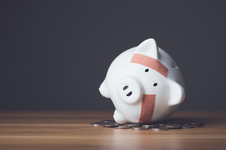 Financial problem, Bankrupt or fail in business concept. White piggy bank with plastic adhesive bandages on wooden desk with dark copy space wall background. Fail, Bankrupt or unsuccessful idea.の写真素材