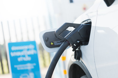 Concepts about using electric cars. An electric car user is holding a black charger to recharge an electric car. The use of electric cars as the latest alternative energy source in Thailand.の写真素材