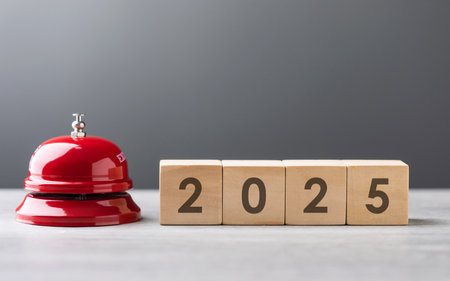 Red service bell and a wooden block displaying 2025 are placed side by side, symbolizing a call to...