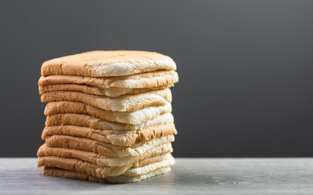 Slices of bread stacked on a gray wooden table against a dark gray background. The image symbolizes the connection between food, nutrition, and maintaining good health.の写真素材
