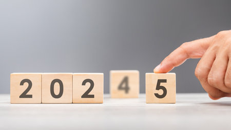 A hand replaces "2024" with "2025" using number blocks, symbolizing the transition into the new year, representing change, progress, and the ongoing passage of timeの写真素材