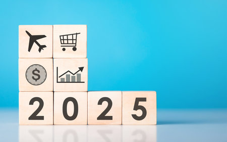 A wooden block with '2025' and business icons written on it, placed on a wooden table against a soft...