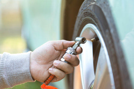 A car owner inflates a tire, highlighting the importance of tire maintenance and pressure checks to ensure safe, smooth travel and readiness before a journeyの写真素材