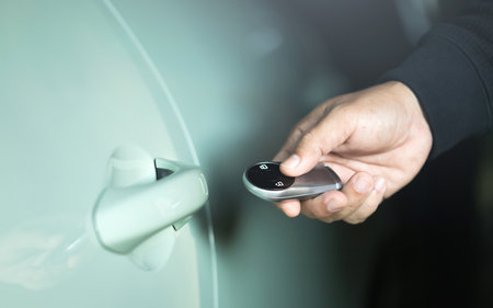 Man's hand holding a car remote to unlock the vehicle. The image represents the concept of using a car remote, highlighting the role of remote battery power in accessing and securing the carの写真素材