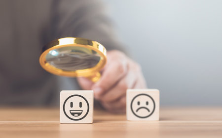 Man choosing between a happy and sad face on wooden blocks, ultimately selecting the happy one. The concept of starting each day with positivity, emphasizing the importance of a bright outlookの写真素材