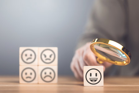 Man choosing between a happy and sad face on wooden blocks, ultimately selecting the happy one. The concept of starting each day with positivity, emphasizing the importance of a bright outlookの写真素材