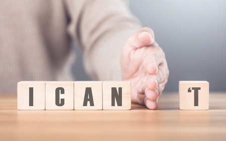 Hand separates the letter "T" from the word "I CAN'T" transforming it into "CAN" The image symbolizes overcoming obstacles, shifting from doubt to empowerment, and embracing a positive mindsetの写真素材