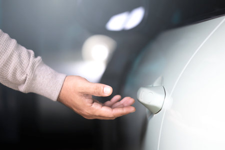 Man's hand reaching to open a car door. The image represents the concept of vehicle usage, emphasizing the everyday action of accessing and using a car responsiblyの写真素材