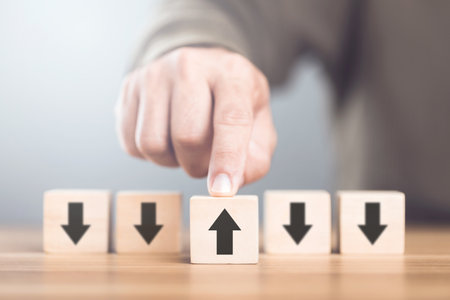 Man selecting an arrow symbol on wooden blocks, symbolizing the concept of thinking in different directions and exploring alternative perspectives in decision-makingの写真素材