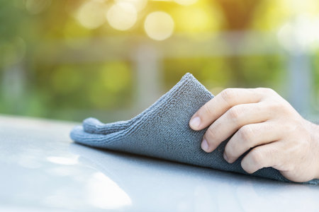 A car owner holds a gray chamois cloth, ready to clean the vehicle. Image emphasizes the importance of selecting the right material for car care, highlighting effective and gentle cleaning techniquesの写真素材