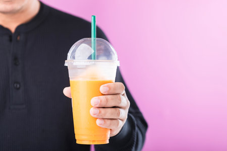 Man enjoying a glass of Thai milk tea, symbolizing the allure of sweet drinks. Highlights the potential health risks of high-sugar beverages, including the risk of obesityの写真素材