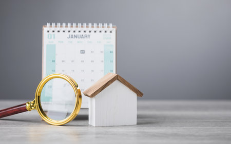 A 2025 calendar, house model, and magnifying glass on a table. The search for an auspicious date to move into a new home. This reflects the tradition of finding the perfect timing for a fresh startの写真素材