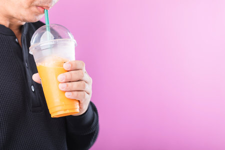Man enjoying a glass of Thai milk tea, symbolizing the allure of sweet drinks. Highlights the potential health risks of high-sugar beverages, including the risk of obesityの写真素材