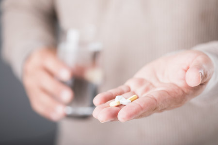 A man holding a glass of cold water and a pill, illustrating the common misconception of taking medication with cold water. Highlights the potential risks and importance of proper medication practicesの写真素材