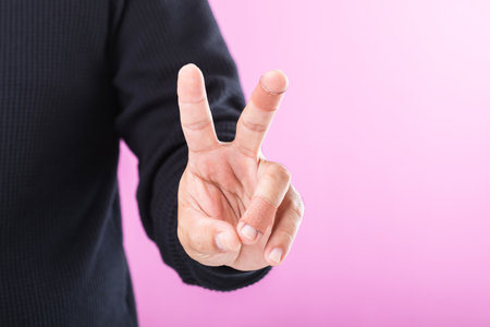 A hand with bandages or plaster on the index and middle fingers forming a 'V' sign, symbolizing resilience and the ability to keep working and going despite minor injuriesの写真素材