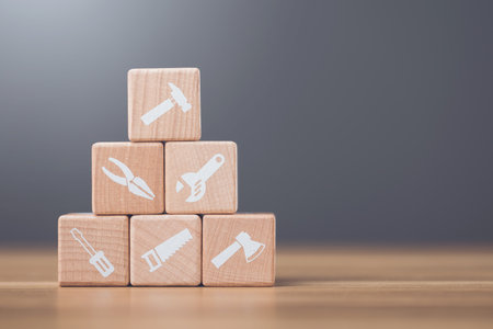 Wooden blocks marked with tool symbols represent home repair and maintenance essentials. This image...