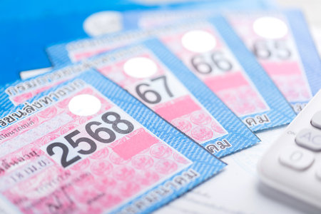 Close-up of Thailand's 2025 vehicle tax sticker placed beside a calculator, emphasizing the importance of calculating and planning for annual vehicle tax payments and financial responsibilitiesの写真素材