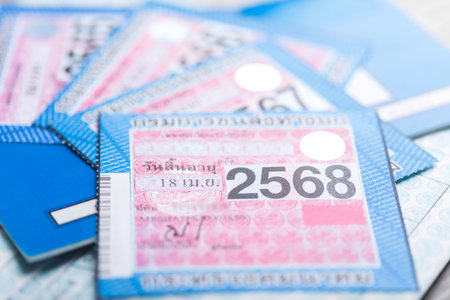 Close-up of Thailand's 2025 vehicle tax sticker placed beside a calculator, emphasizing the importance of calculating and planning for annual vehicle tax payments and financial responsibilitiesの写真素材